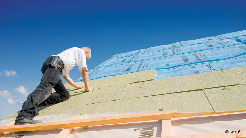 Ein Bauarbeier saniert ein Dach