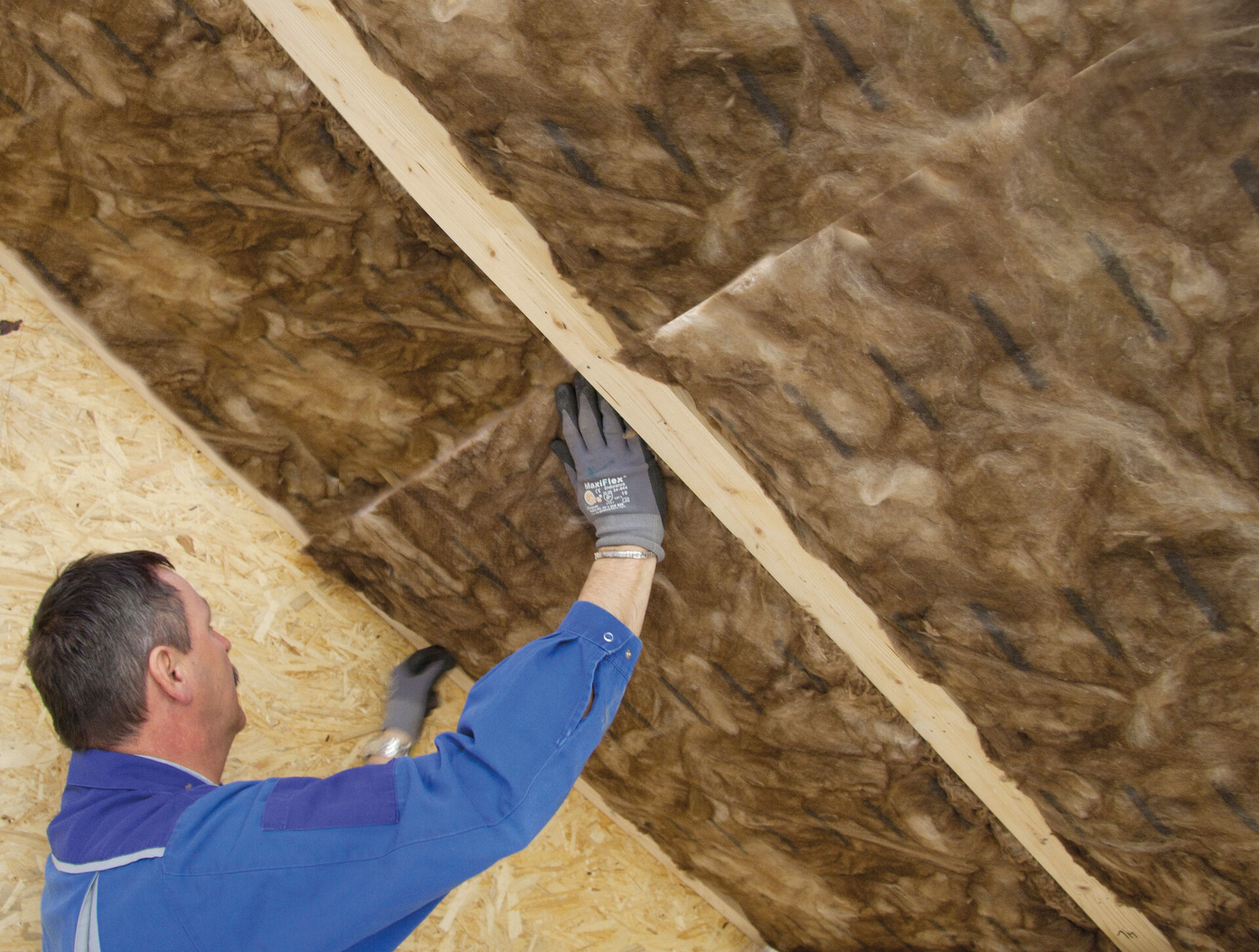 Ein Bauarbeiter dämmt einen Dachboden mit Aufsparrendämmung