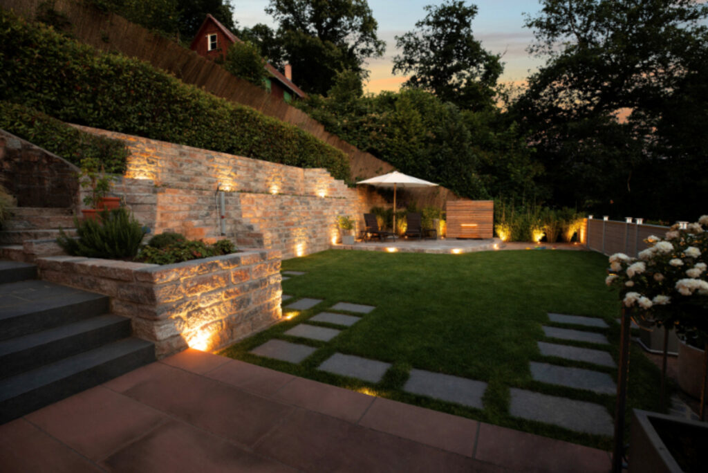 Eine Gartenmauer mit Terrassenbeleuchtung